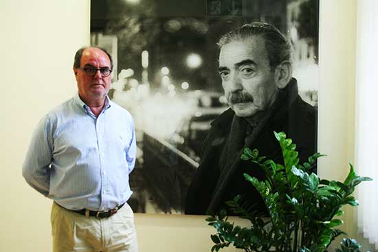 "Rafael de la Dueña, bibliotecario de la Biblioteca Juan Gelman, junto a la imagen del autor que da nombre a la misma y recibe al usuario de la Biblioteca en el Instituto Cervantes de Viena" "Rafael de la Dueña, bibliotecario de la Biblioteca Juan Gelman, junto a la imagen del autor que da nombre a la misma y recibe al usuario de la Biblioteca en el Instituto Cervantes de Viena"